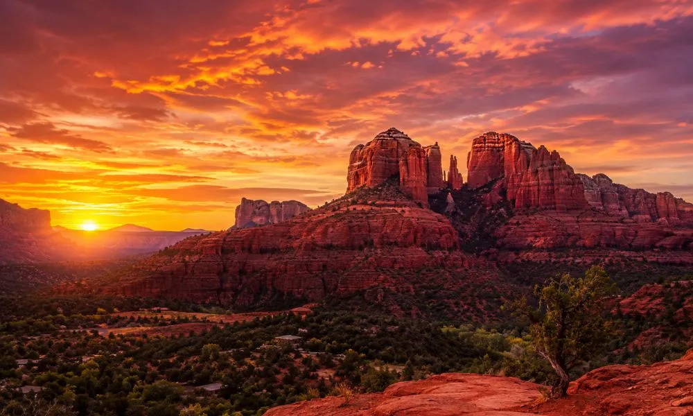 Surreal sunset at Cathedral Rock in Sedona, Arizona, with vivid orange and crimson hues reflecting off the red sandstone rock formations against a deep blue sky