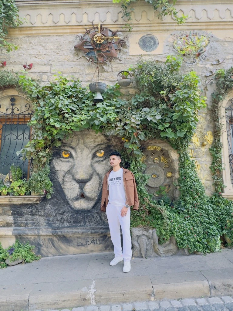 Traveler standing near Ali Shamsi lion mural in Old City Baku