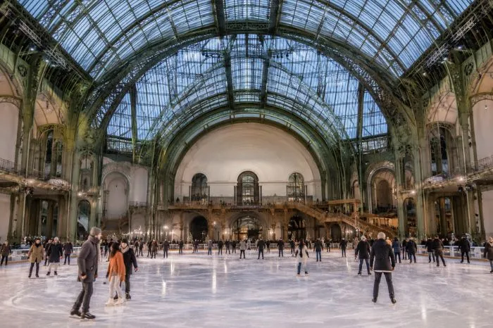 Visitors ice skating beneath the glass roof of the Grand Palais in Paris