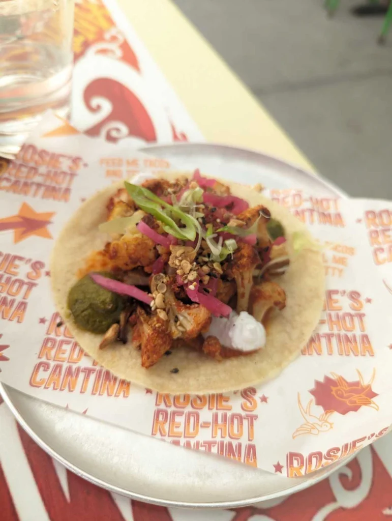 Close-up of a taco topped with pickled red onions, sliced green chilies, and fresh herbs at Rosie's Red-Hot Cantina