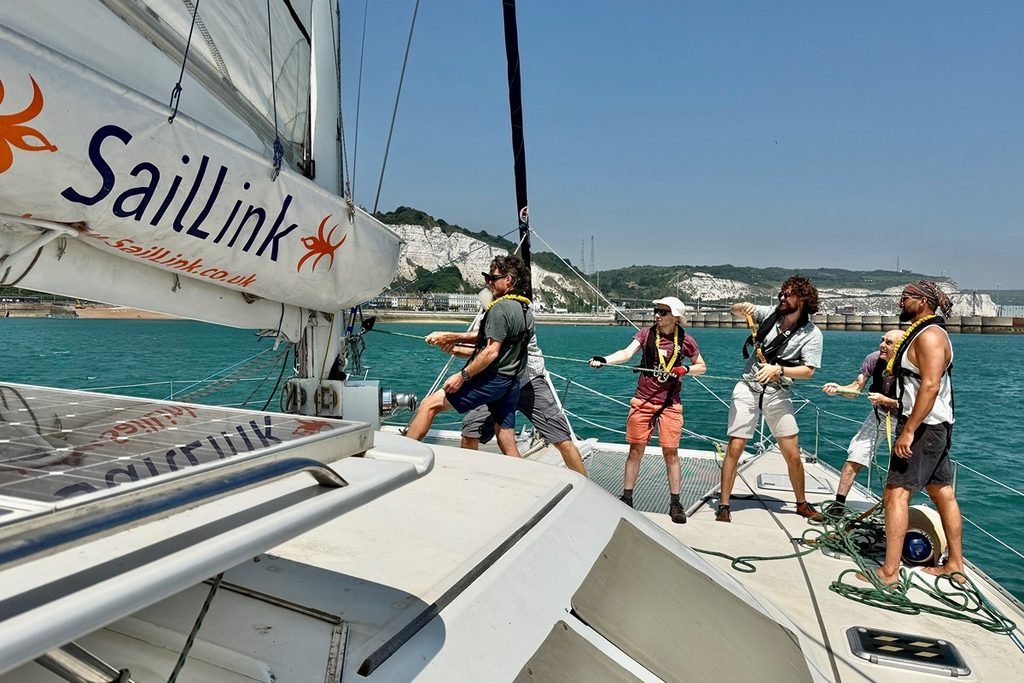 Passengers Help Hoist the Sail on Echoes the SailLink Catamaran