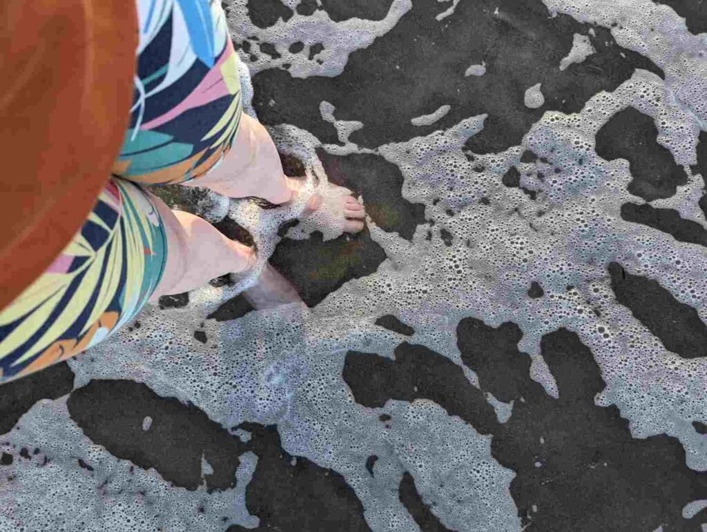 Walking barefoot through shallow waves at Mount Maunganui Main Beach